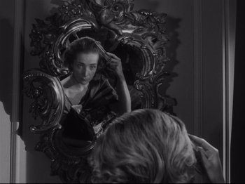 Movie still from “The Exterminating Angel” (1962), directed by Luis Buñuel – A black and white photo of a woman looking in the mirror; Close Up shot, Over the shoulder angle