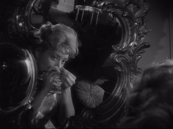 Movie still from “The Exterminating Angel” (1962), directed by Luis Buñuel – A black and white photo of a woman eating a sandwich; Close Up shot, High angle