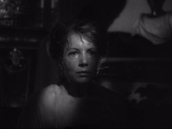 Movie still from “The Exterminating Angel” (1962), directed by Luis Buñuel – A black - and - white photo of a woman in a dark room; Close Up shot, Over the shoulder angle