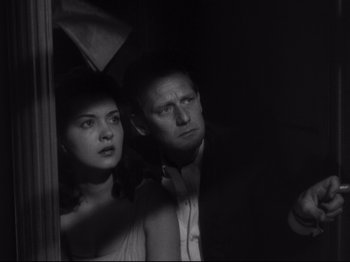 Movie still from “The Exterminating Angel” (1962), directed by Luis Buñuel – A man and a woman standing next to each other in a dark room; Close Up shot, Low angle