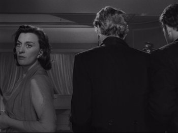 Movie still from “The Exterminating Angel” (1962), directed by Luis Buñuel – A man and a woman standing next to each other in front of a mirror; Medium shot, Over the shoulder angle