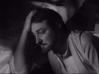 Movie still from “The Exterminating Angel” (1962), directed by Luis Buñuel – A black and white photo of a man smoking a cigarette; Close Up shot, High angle