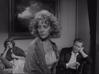 Movie still from “The Exterminating Angel” (1962), directed by Luis Buñuel – A man and a woman sitting in front of a painting; Medium shot, Over the shoulder angle