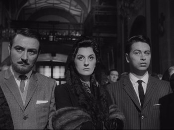 Movie still from “The Exterminating Angel” (1962), directed by Luis Buñuel – A group of people standing next to each other in a room; Medium shot, Low angle