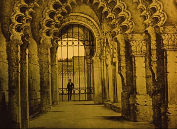 Movie still from “The Fabulous Baron Munchausen” (1962), directed by Karel Zeman – A person standing in front of an iron gate in an archway; Extreme Wide shot, Low angle