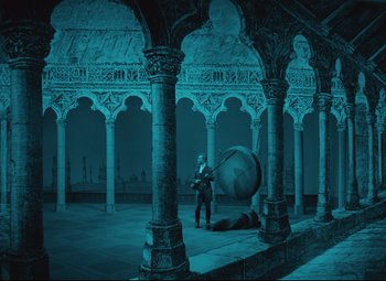 Movie still from “The Fabulous Baron Munchausen” (1962), directed by Karel Zeman – A man is standing in a courtyard holding a large object; Extreme Wide shot, High angle