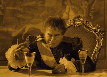 Movie still from “The Fabulous Baron Munchausen” (1962), directed by Karel Zeman – A man sitting at a table with a glass of wine; Medium shot, High angle