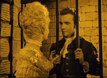 Movie still from “The Fabulous Baron Munchausen” (1962), directed by Karel Zeman – A man and a woman are standing next to each other in front of a brick wall; Medium shot, High angle