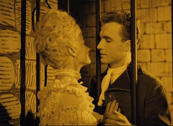 Movie still from “The Fabulous Baron Munchausen” (1962), directed by Karel Zeman – A man and a woman standing next to each other in front of a cage; Medium shot, Low angle