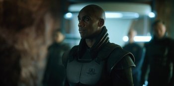 Movie still from “Altered Carbon” (2018), created by Laeta Kalogridis – A man in a black suit is looking to his left; Close Up shot, Over the shoulder angle