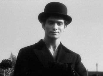 Movie still from “The Fiancés of the Bridge Mac Donald” (1961), directed by Agnès Varda – A man wearing a top hat and a jacket; Close Up shot, Low angle