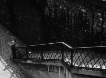 Movie still from “The Fiancés of the Bridge Mac Donald” (1961), directed by Agnès Varda – A black and white photo of a railing and steps; Extreme Wide shot, High angle