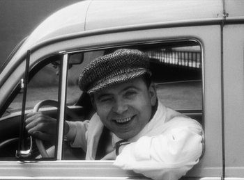 Movie still from “The Fiancés of the Bridge Mac Donald” (1961), directed by Agnès Varda – A black and white photo of a man driving a car; Close Up shot, Low angle