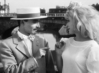 Movie still from “The Fiancés of the Bridge Mac Donald” (1961), directed by Agnès Varda – A man and a woman are standing next to each other; Medium shot, Over the shoulder angle