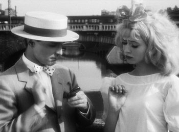 Movie still from “The Fiancés of the Bridge Mac Donald” (1961), directed by Agnès Varda – A man and a woman standing next to each other in front of a body of water; Medium shot, Over the shoulder angle