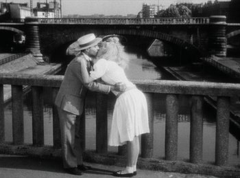 Movie still from “The Fiancés of the Bridge Mac Donald” (1961), directed by Agnès Varda – A man and a woman kissing near a bridge; Wide shot, Over the shoulder angle