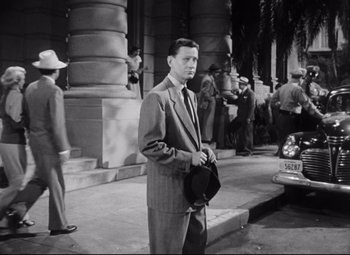 Movie still from “The File on Thelma Jordon” (1949), directed by Robert Siodmak – A black and white photo of a man standing on a sidewalk; Medium shot, High angle