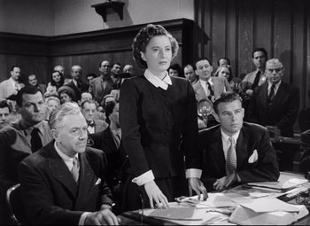 Movie still from “The File on Thelma Jordon” (1949), directed by Robert Siodmak – An old photo of a woman standing in front of a group of people; Medium shot, High angle