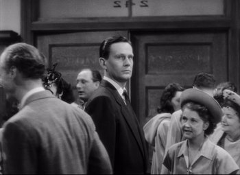 Movie still from “The File on Thelma Jordon” (1949), directed by Robert Siodmak – Black and white photograph of a man in a suit; Medium shot, Over the shoulder angle