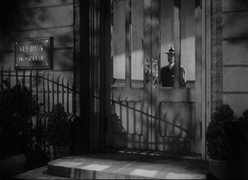 Movie still from “The File on Thelma Jordon” (1949), directed by Robert Siodmak – A black and white photo of a man in a uniform looking out of a door; Wide shot, Low angle