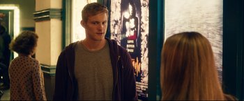 Movie still from “The Final Girls” (2015), directed by Todd Strauss-Schulson – A man standing in front of a movie poster; Medium shot, Over the shoulder angle