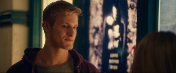 Movie still from “The Final Girls” (2015), directed by Todd Strauss-Schulson – A man with blonde spiky hair looking to his left; Close Up shot, Over the shoulder angle