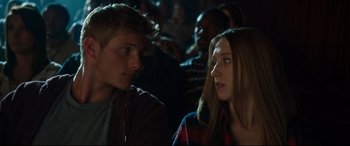 Movie still from “The Final Girls” (2015), directed by Todd Strauss-Schulson – A man and a woman sitting next to each other in a crowd; Close Up shot, Over the shoulder angle