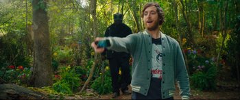 Movie still from “The Final Girls” (2015), directed by Todd Strauss-Schulson – A man holding a video game controller in the woods; Medium shot, Over the shoulder angle