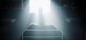 Movie still from “The Final Girls” (2015), directed by Todd Strauss-Schulson – A man sitting in a hospital bed in a room with a window; Wide shot, Low angle