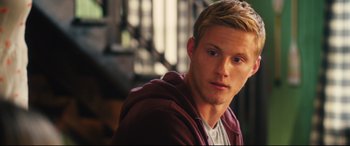 Movie still from “The Final Girls” (2015), directed by Todd Strauss-Schulson – A man with blonde hair sitting in front of a railing; Close Up shot, Over the shoulder angle
