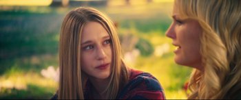 Movie still from “The Final Girls” (2015), directed by Todd Strauss-Schulson – A young girl is sitting in the grass; Close Up shot, Over the shoulder angle