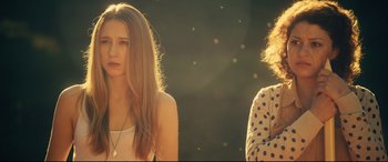 Movie still from “The Final Girls” (2015), directed by Todd Strauss-Schulson – Two young women standing next to each other in the sunlight; Medium shot, Low angle