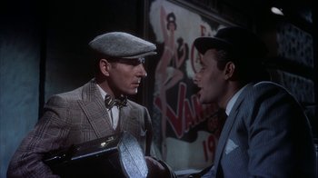 Movie still from “The Five Pennies” (1959), directed by Melville Shavelson – A man in a suit and a hat talking to another man in a suit and a hat; Medium shot, Over the shoulder angle