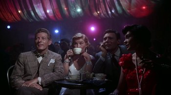 Movie still from “The Five Pennies” (1959), directed by Melville Shavelson – A group of men and women sitting at a table; Medium shot, Low angle