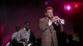 Movie still from “The Five Pennies” (1959), directed by Melville Shavelson – A man in a brown suit playing a trumpet; Medium shot, Low angle