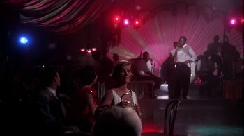Movie still from “The Five Pennies” (1959), directed by Melville Shavelson – A group of people sitting in a room with a microphone; Wide shot, Over the shoulder angle