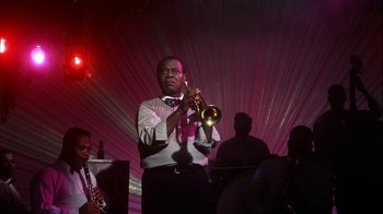 Movie still from “The Five Pennies” (1959), directed by Melville Shavelson – A man holding a trumpet while standing next to a group of people; Medium shot, Low angle