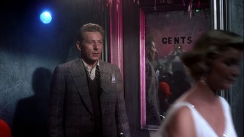 Movie still from “The Five Pennies” (1959), directed by Melville Shavelson – A man wearing a suit and tie standing in front of a mirror; Medium shot, Over the shoulder angle