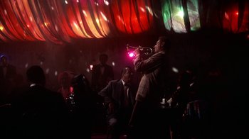 Movie still from “The Five Pennies” (1959), directed by Melville Shavelson – A man playing a trumpet in front of a group of people; Wide shot, Low angle