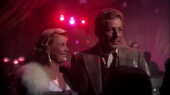 Movie still from “The Five Pennies” (1959), directed by Melville Shavelson – A man and a woman standing next to each other in front of lights; Close Up shot, Low angle