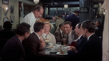 Movie still from “The Five Pennies” (1959), directed by Melville Shavelson – A group of people sitting at a table with plates of food on it; Medium shot, Over the shoulder angle