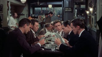 Movie still from “The Five Pennies” (1959), directed by Melville Shavelson – A group of men sitting at a table looking at papers; Medium shot, High angle