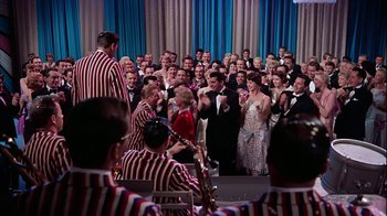 Movie still from “The Five Pennies” (1959), directed by Melville Shavelson – A group of people standing in front of each other on a stage; Wide shot, High angle