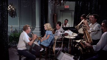 Movie still from “The Five Pennies” (1959), directed by Melville Shavelson – A group of people sitting at a table with instruments; Wide shot, High angle