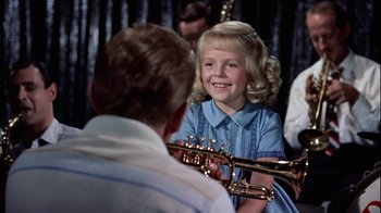 Movie still from “The Five Pennies” (1959), directed by Melville Shavelson – A little girl sitting in front of a man holding a trumpet; Medium shot, Over the shoulder angle