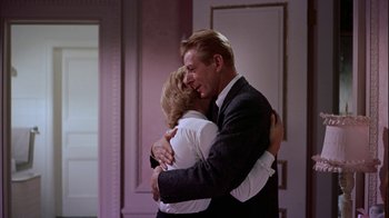 Movie still from “The Five Pennies” (1959), directed by Melville Shavelson – A man and a woman hugging in a room; Medium shot, Over the shoulder angle