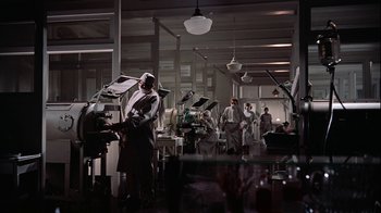 Movie still from “The Five Pennies” (1959), directed by Melville Shavelson – A group of people working in an industrial setting; Extreme Wide shot, Low angle