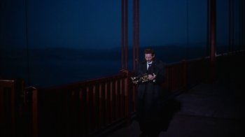 Movie still from “The Five Pennies” (1959), directed by Melville Shavelson – A man standing on a bridge playing a guitar; Extreme Wide shot, High angle