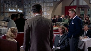 Movie still from “The Five Pennies” (1959), directed by Melville Shavelson – A group of people sitting around a restaurant; Wide shot, Over the shoulder angle