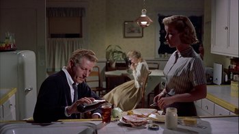 Movie still from “The Five Pennies” (1959), directed by Melville Shavelson – A man sitting at a dinner table looking at his cell phone; Medium shot, Low angle